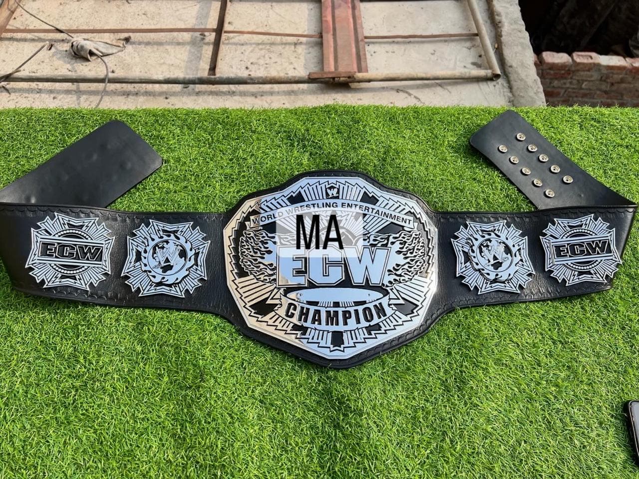 Extreme Silver Chrome Championship Belt laid flat, showing the centre plate and side plates on a black leather strap