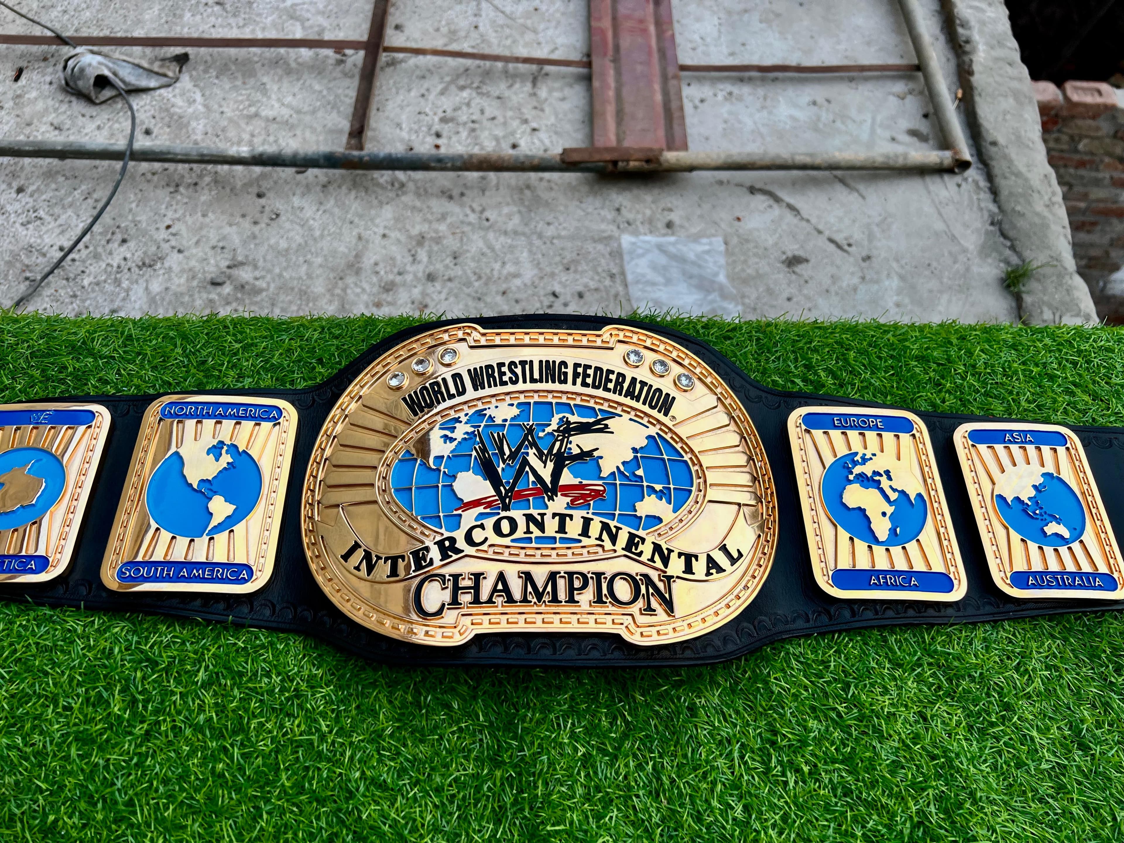 Oval Continental Championship Belt laid flat, showing the centre plate and side plates on a black leather strap