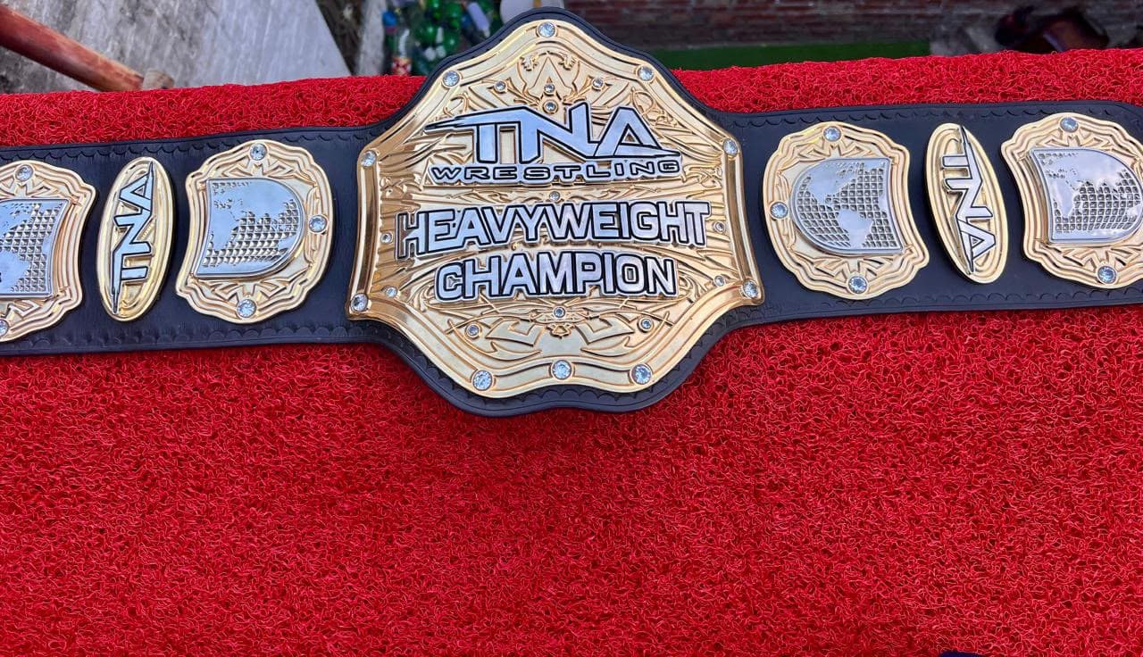 Stacked Gold heavyweight championship belt laid flat, showing the layered gold centre plate set with clear stones