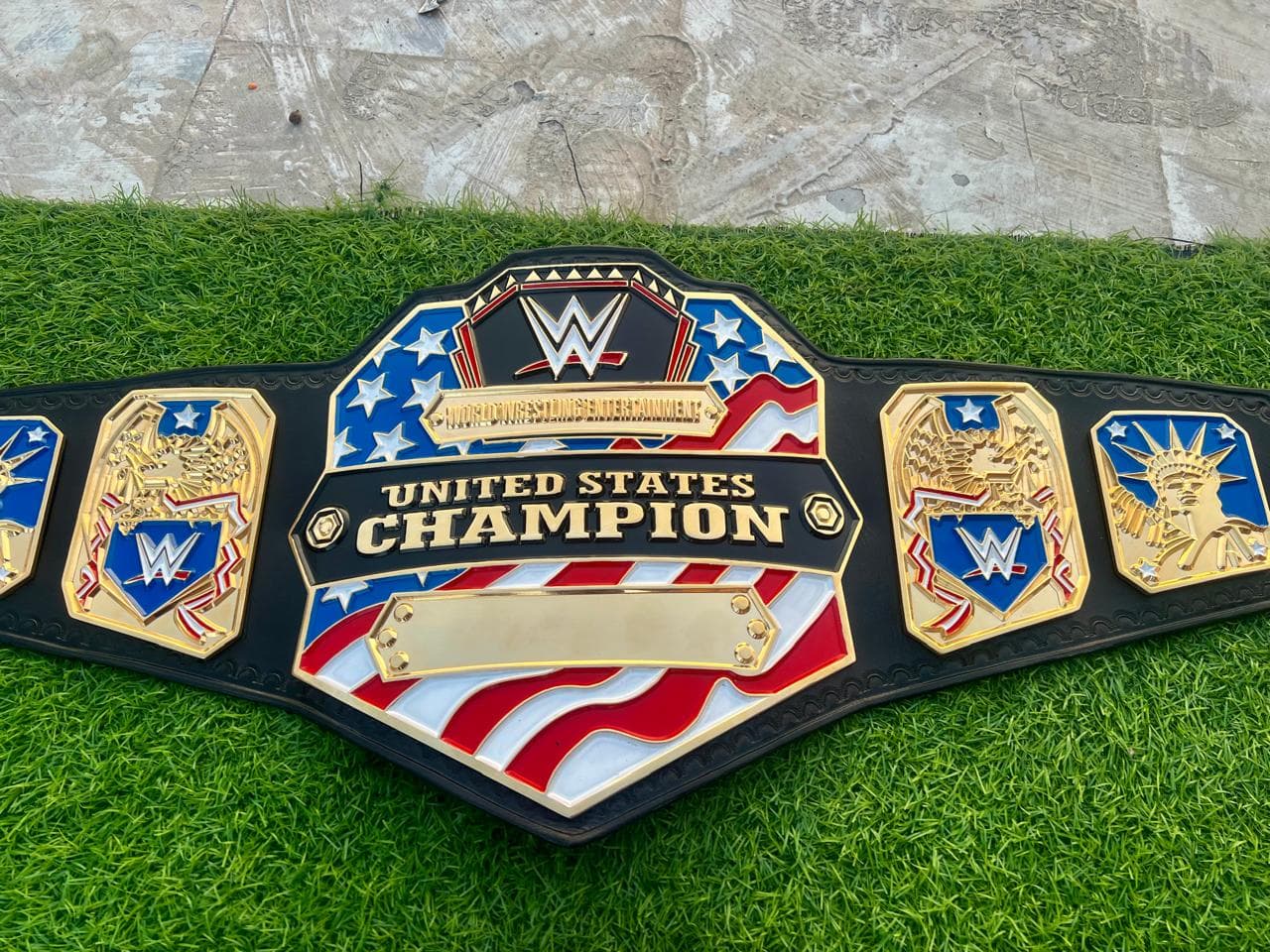 United States Champion Style Belt laid flat, showing the centre plate and side plates on a black leather strap