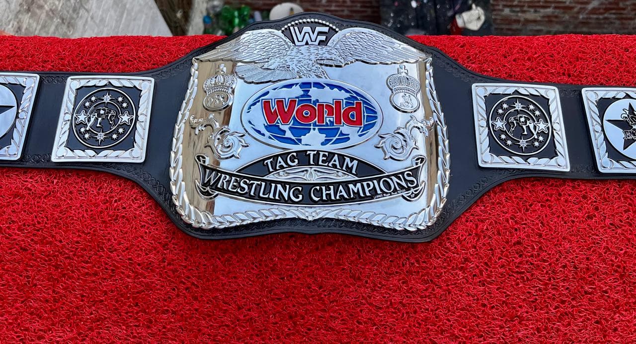 World Tag Team Silver Championship Belt laid flat, showing the centre plate and side plates on a black leather strap